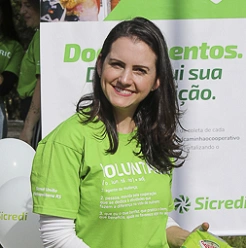  mulher branca com cabelo preto e blusa verde sorrindo para camera 