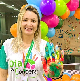  mulher branca e loira com camisa branca com verde e mão pintada com tintas de diversas cores 