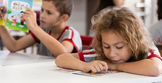  crianças desenvolvendo trabalho em sala de aula 